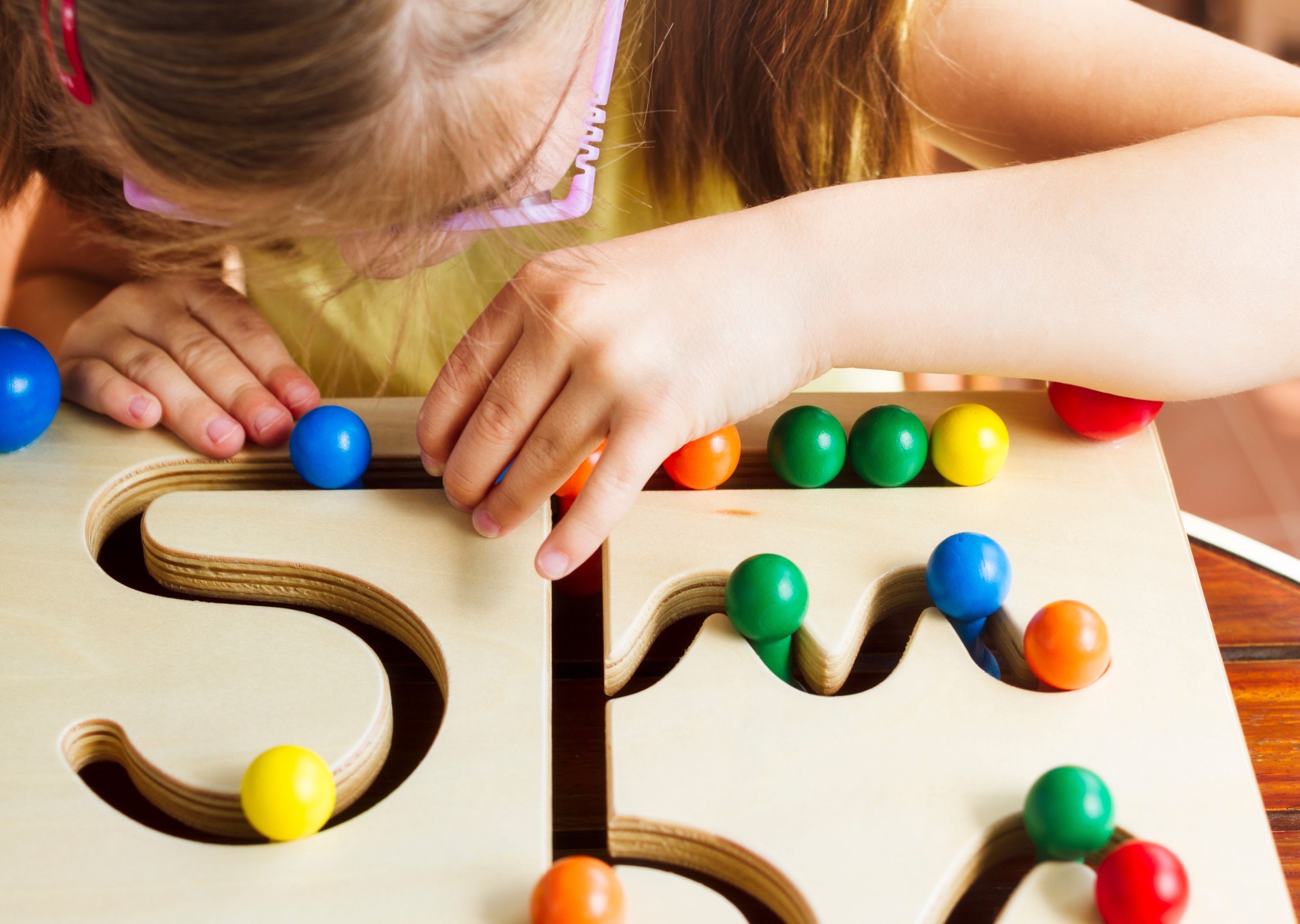 Child with glasses playing with pathfinder toy board